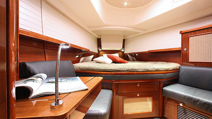 Schlafbereich mit Arbeitsbereich einer Yacht mit rötlichem Holz glänzend lackiert