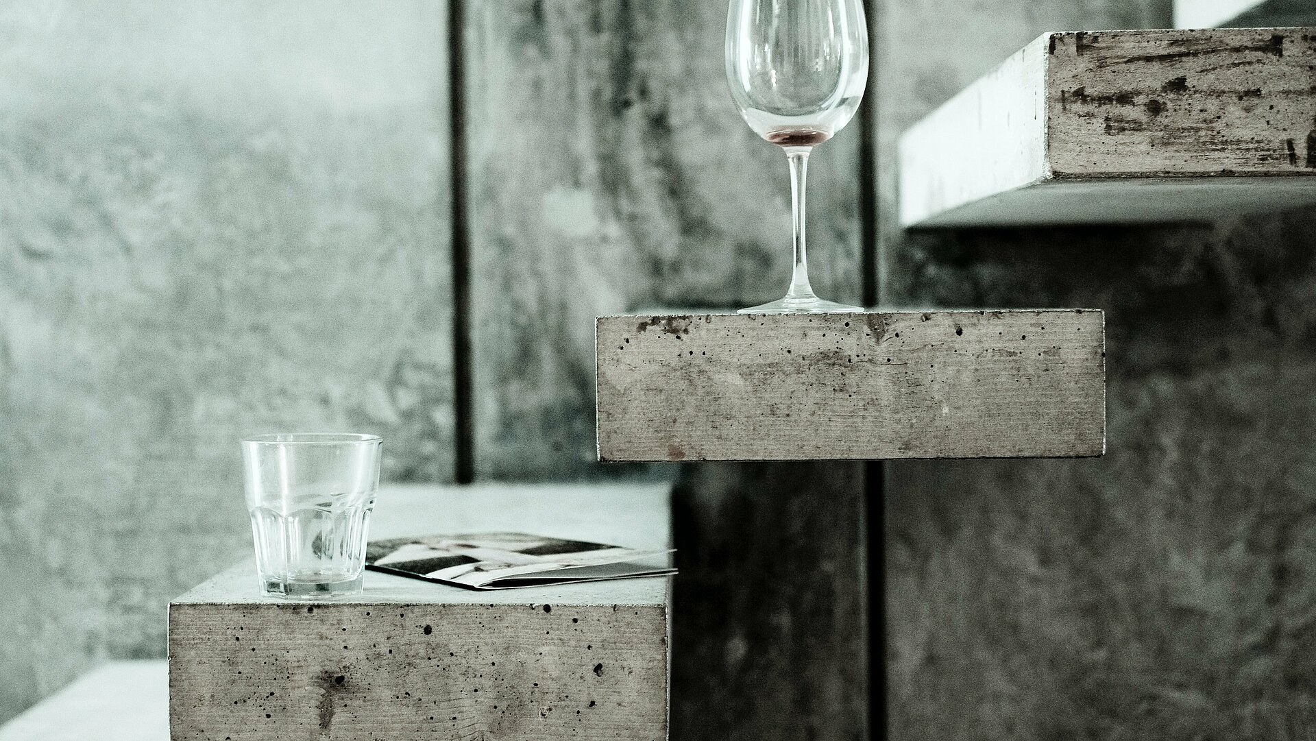 Wasserglas und Weinglas auf Betonfläche