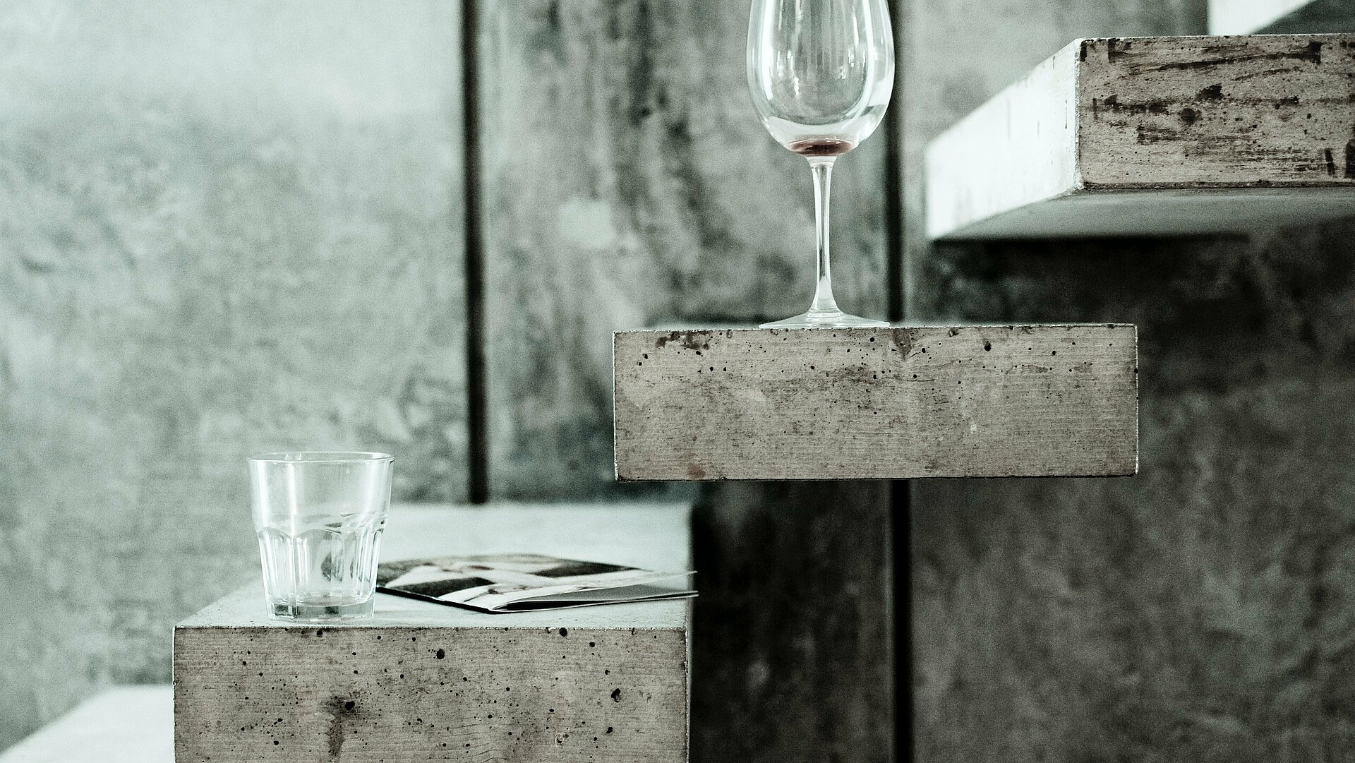 Wasserglas und Weinglas auf Betonfläche