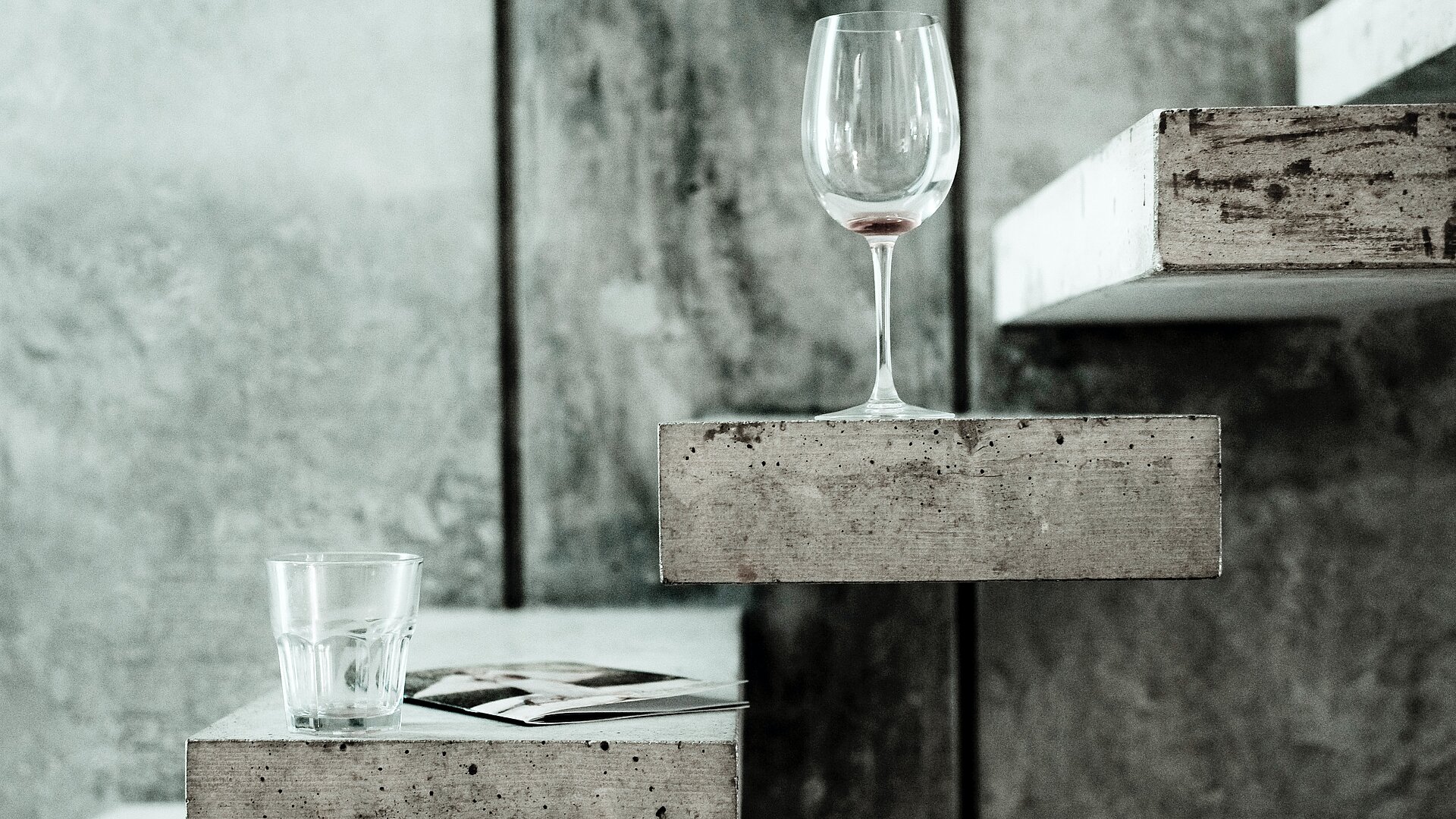 Wasserglas und Weinglas auf Betonfl&auml;che