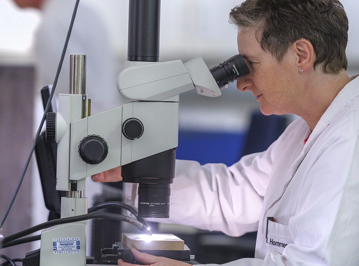 Eine Frau im Labor schaut in ein Mikroskop