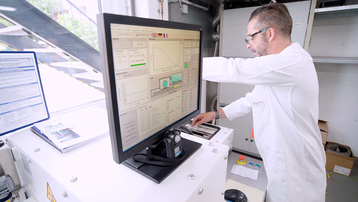 Mann in Arbeitskleidung vor einer Maschine der Elektronenstrahlhärtung