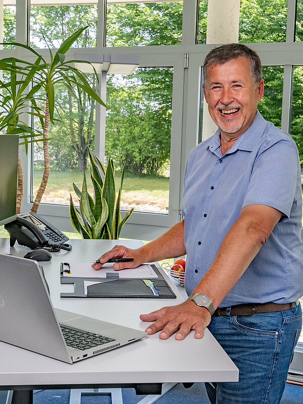 Mann stehend an seinem Arbeitsplatz mit verstellbarem Schreibisch