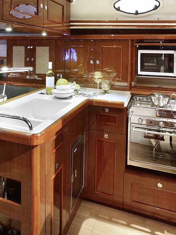 Küche einer Yacht mit rötlichem Holz glänzend lackiert